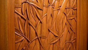 A wooden door with intricate carvings of bamboo leaves and stems.