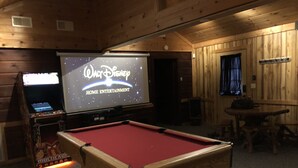 Et billardbord i et rum med trævægge og et projektorskærm, der viser "Walt Disney Home Entertainment".