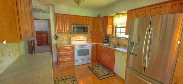 A kitchen with wooden cabinets, a stainless steel refrigerator, a microwave, an oven, and a dishwasher.