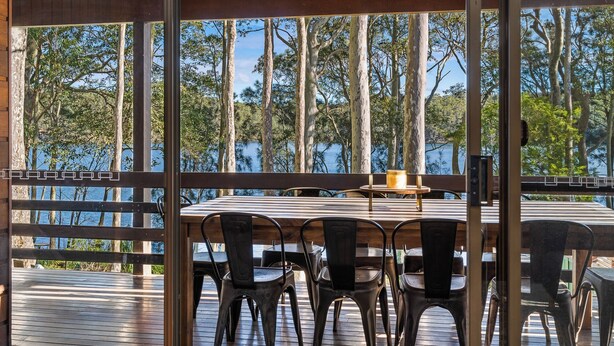 An outdoor dining area with a table and chairs, overlooking a body of water and trees. - Kings Point Lake House - Family Getaway
Wake up to peaceful lake views (Kings Point)