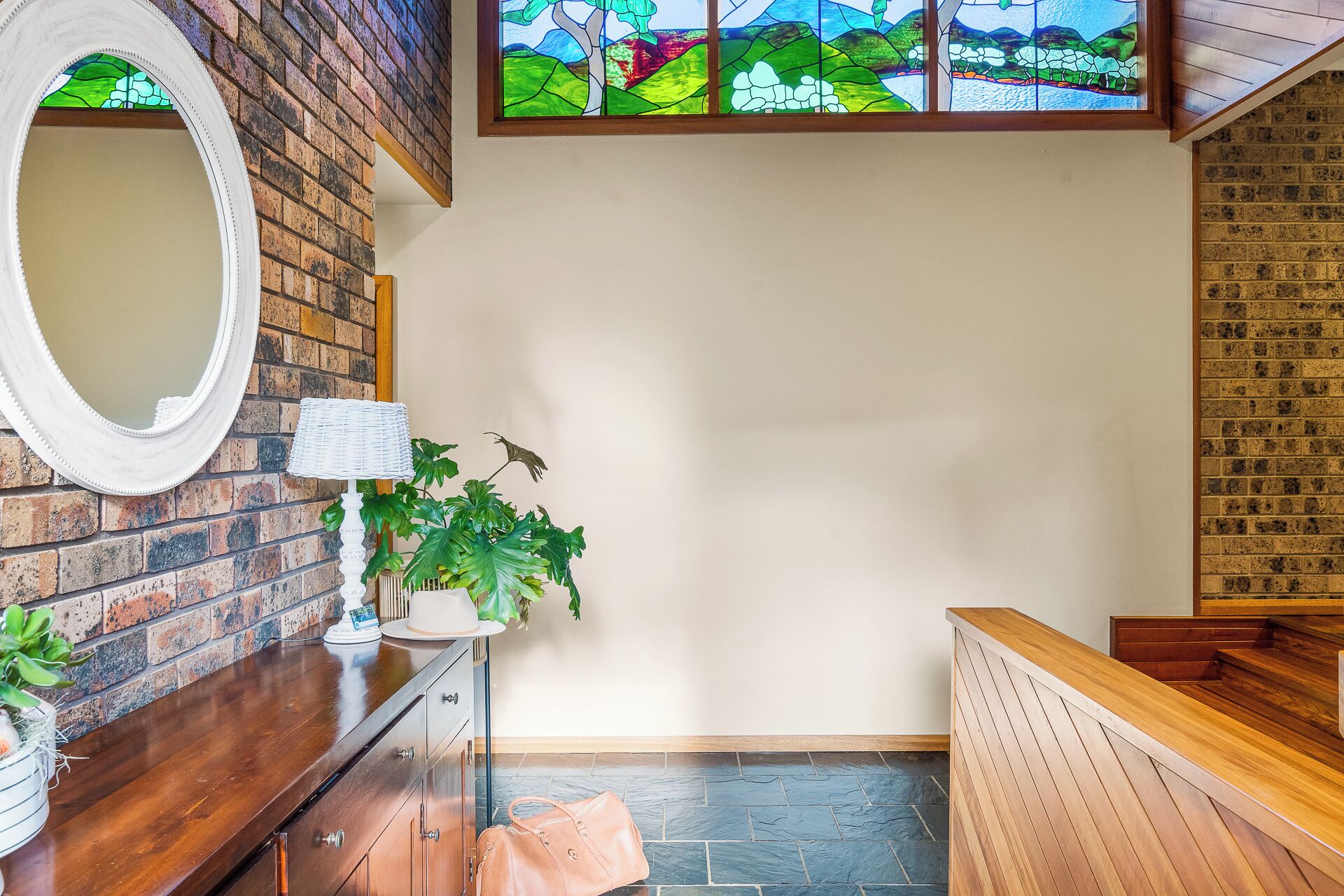 A reception area with a wooden reception desk, a white lamp, and a large mirror on the wall.