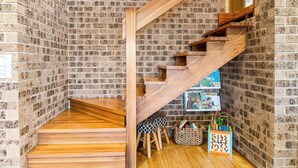 A wooden staircase with a brick wall background, a wooden floor, and a small seating area with stools and a basket. - Kings Point Lake House - Family Getaway
Wake up to peaceful lake views (Kings Point)