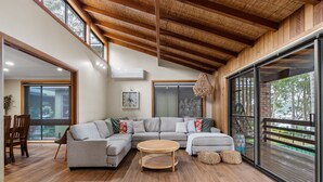 A modern living room with a sectional sofa, a round wooden coffee table, and a large sliding glass door to the outdoors. - Kings Point Lake House - Family Getaway
Wake up to peaceful lake views (Kings Point)