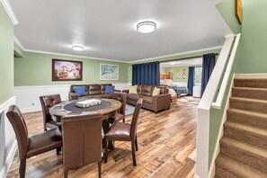 Amplia sala de estar con una mesa redonda y sillones de cuero, un sofá de cuero marrón y una escalera que conduce a un nivel superior.