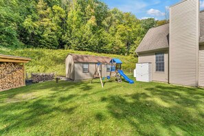 A backyard with a wooden playset, a shed, and a house.
