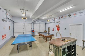 Une pièce équipée d’une table de ping-pong, d’une table de billard et d’une table de jeu de flipper.