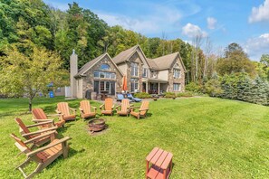 Une grande maison en pierre dotée d’une pelouse bien entretenue et d’un espace extérieur aménagé pour se détendre.