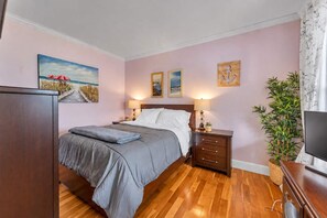 Un dormitorio con cama, mesitas de noche, televisor y obras de arte en las paredes.