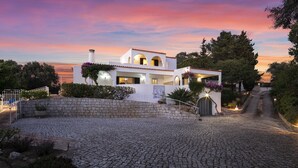 Eine weiße Villa mit Steinfassade, Bogenfenstern und einer Steintreppe zum Eingang.