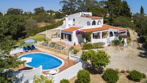 Eine weiße Villa mit Schwimmbad, Sitzgelegenheiten im Freien und einem Garten.