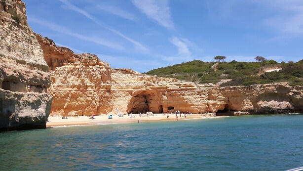 Ein Küstenstrand mit einer felsigen Klippe und einem Höhleneingang.
