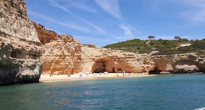Ein Küstenstrand mit einer felsigen Klippe und einem Höhleneingang.