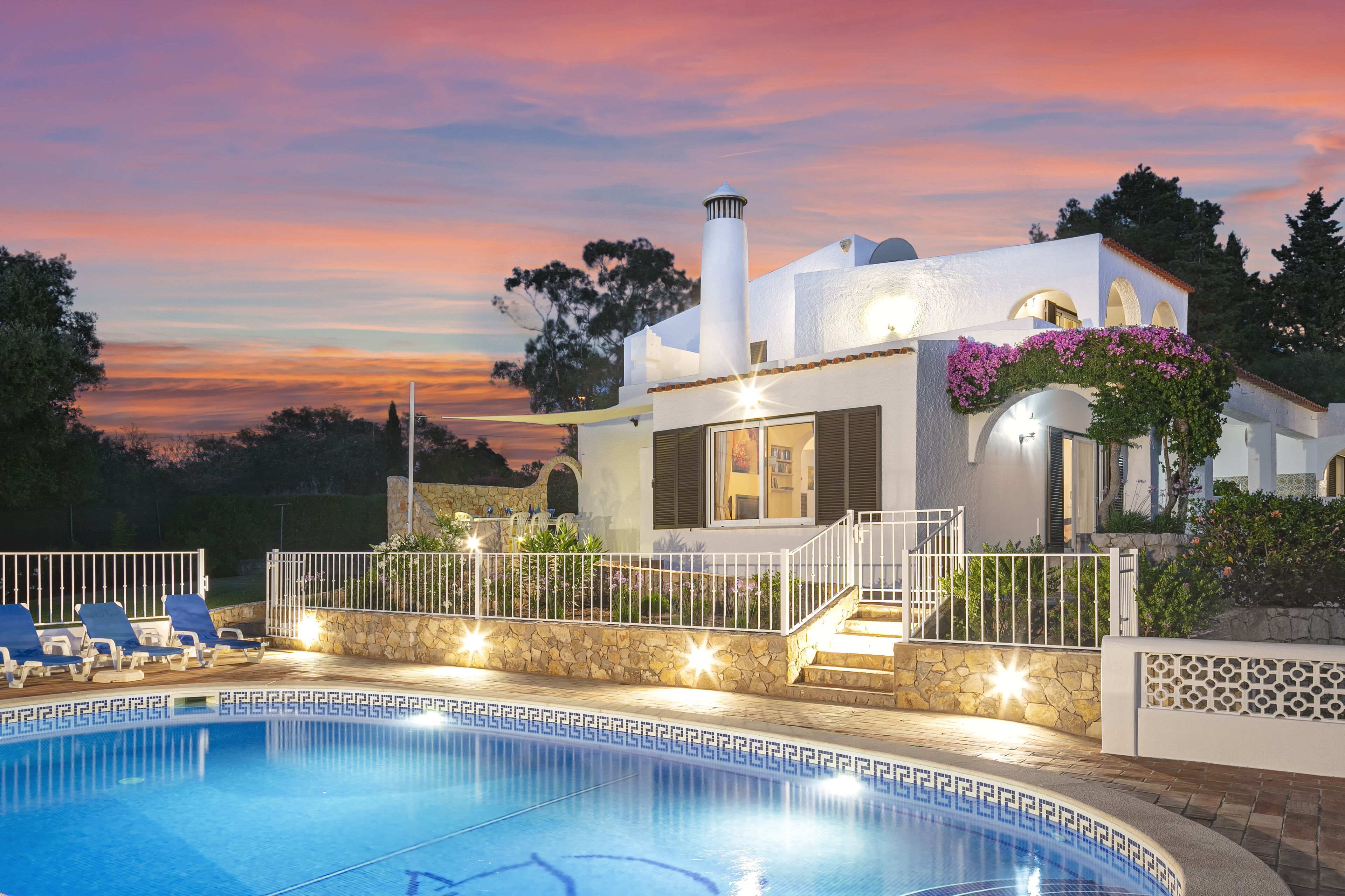 A modern house with a swimming pool, stone walls, and a white exterior.
