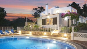 Ein modernes Haus mit Swimmingpool, Steinmauern und heller Fassade.