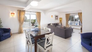 Ein geräumiger Wohnbereich mit Esstisch, Sofas und einem Balkon.