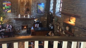 Un interior acogedor con chimenea de piedra, estantes de madera y un candelabro.