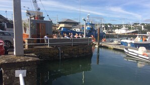 Un puerto deportivo con barcos amarrados, un muro de piedra y un edificio con una grúa.