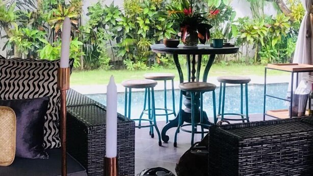 Un espace extérieur accueillant, aménagé avec des meubles en osier, une petite table ronde et des plantes en pot.