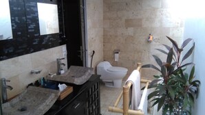 Une salle de bain avec un grand miroir, deux lavabos, des toilettes et un espace douche.