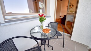 A small round table with a glass top, two black chairs, a vase with red flowers, a plate with croissants, and a cup and saucer. - Vacation apartment by the sea, vacation on the island of Usedom, Apartment VELA ROSA (Swinoujscie)