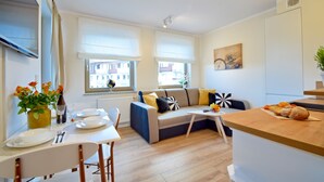 Ein modernes Wohnzimmer mit Sofa, Esstisch und Küchenzeile.