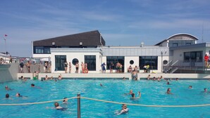 Ein Schwimmbecken mit Personen im Wasser und am Beckenrand.