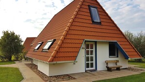 Ein haus mit einem dreieckigen Dach, einer kleinen Veranda und einer Tür.