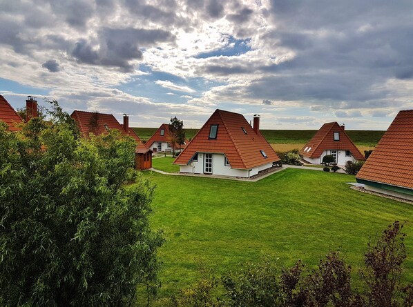 A cluster of traditional houses with pitched roofs and chimneys, surrounded by lush green lawns and trees.