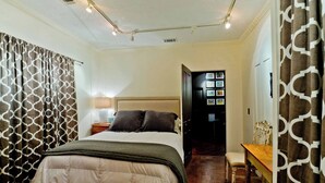 A bedroom with a bed, a bedside table, a chair, a desk, and a bookshelf. - 2BR/2BA Walk to downtown! Near the Beach! Perfect location! The Gallery (Ocean Springs)
