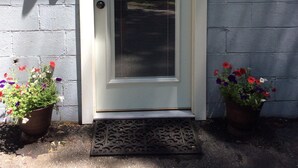 A front door with a number plate, a mailbox, and two potted plants.