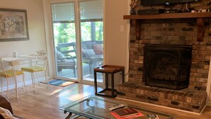 A living room with a fireplace, a glass coffee table, a sofa, and a television mounted on the wall.