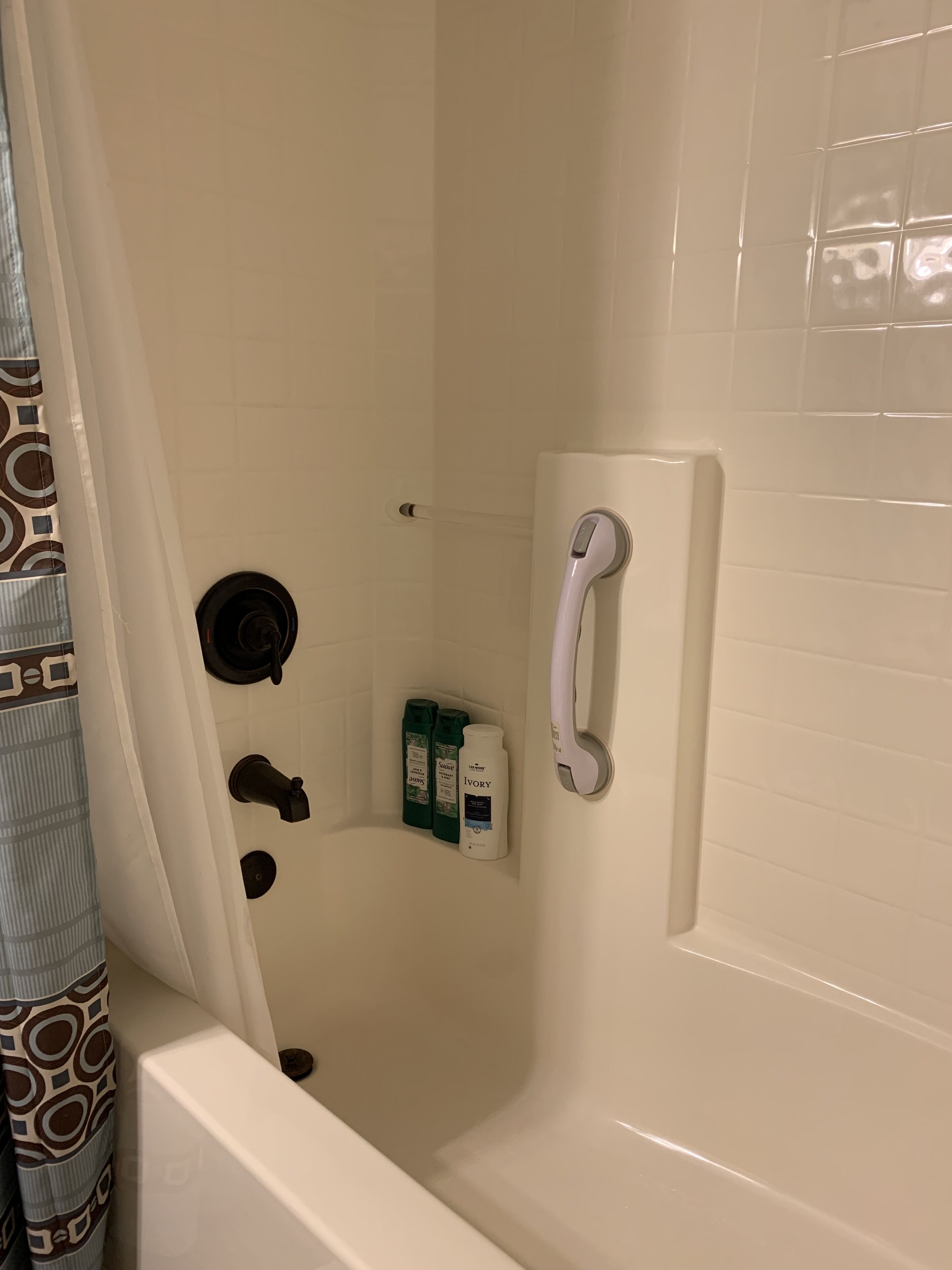 Une salle de bain avec une douche, des toilettes et un sèche-mains. Des articles de toilette sont accrochés au mur.