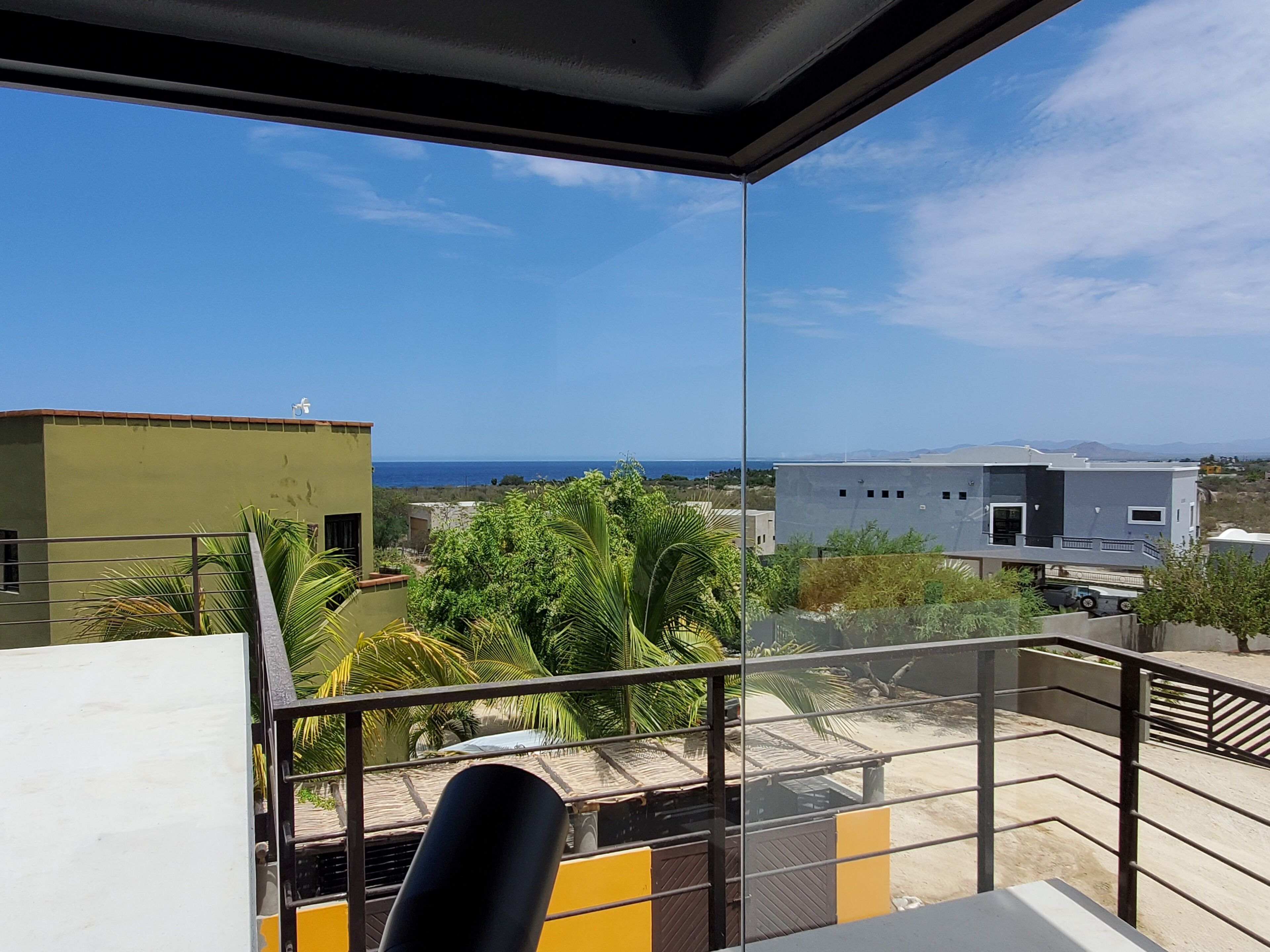 A balcony with a clear view of the sea and surrounding buildings.