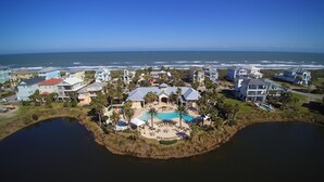 An aerial view of a coastal residential area with houses, a central pool, and two bodies of water. - Beachy Keen Platinum Property with Unbeatable View!   (Palm Coast)