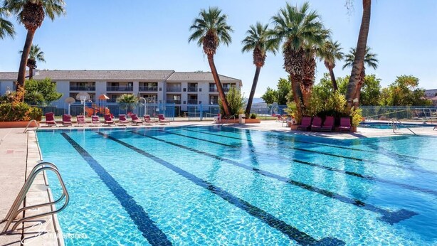 A swimming pool with clear blue water, surrounded by palm trees and lounge chairs. - 3 bedrooms. 4 TV's. Great view, Nice Reviews. (St. George)