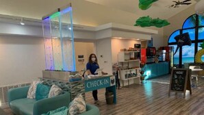 A check-in area with a reception desk, a seating area with teal sofas, and a view of the sea through large windows. - 3 bedrooms. 4 TV's. Great view, Nice Reviews. (St. George)