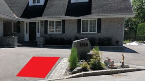 Une maison avec une façade en pierre, un garage et une allée menant à l’entrée, recouverte d’un tapis rouge.