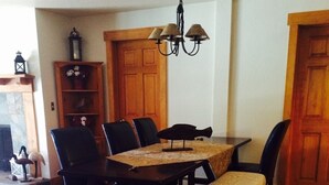 Een eethoek met een houten tafel, stoelen en een bank. Daarboven hangt een kroonluchter.