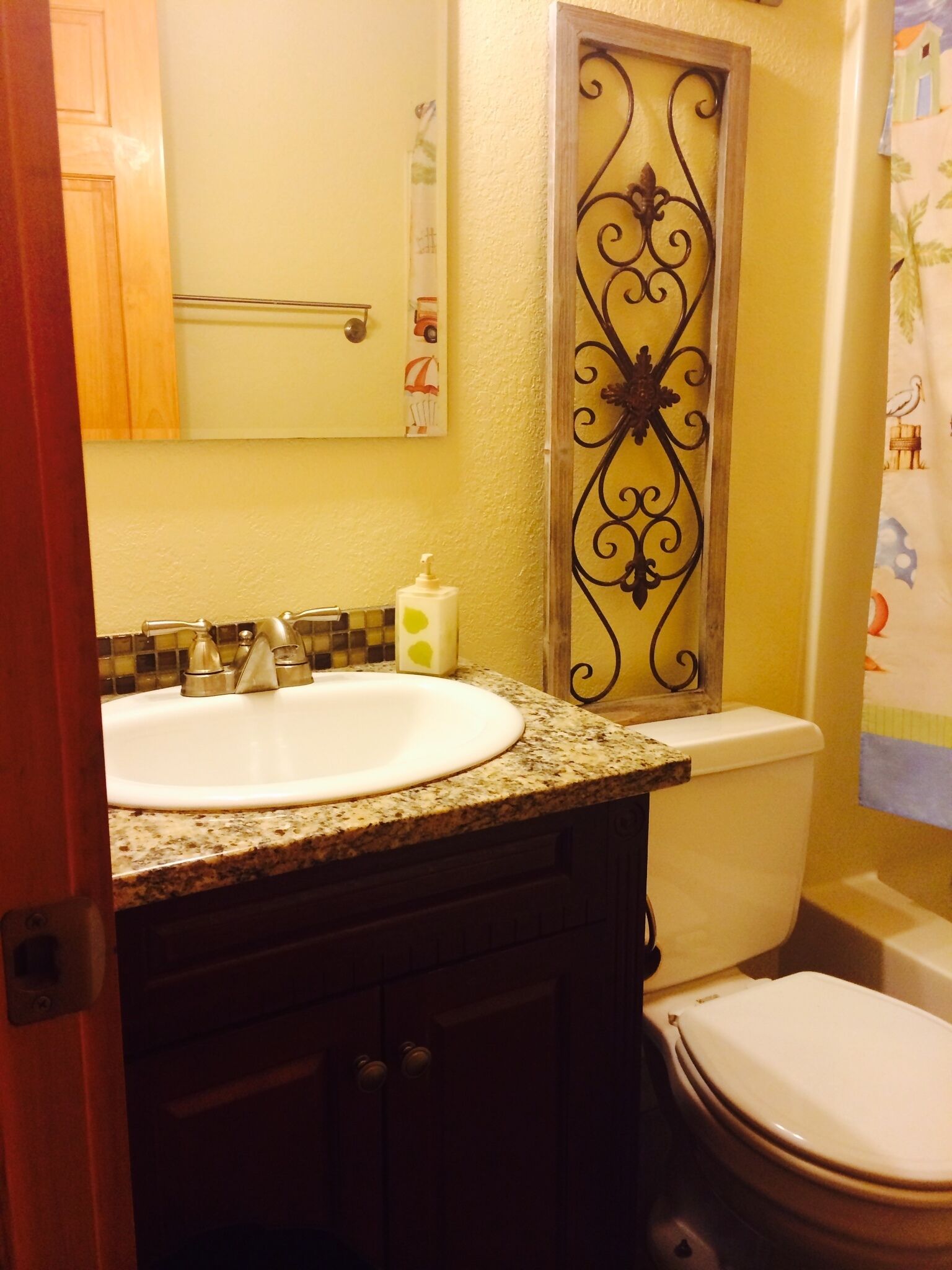 Een badkamer met een wastafel, toilet en een decoratieve metalen lijst.