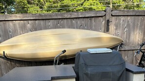 A barbecue grill and a covered grill bag against a brick wall.