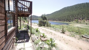A wooden cabin with a balcony overlooking a lake and forested hills. - Fawn Haven on the Lake (Bailey)