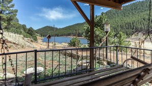 A wooden deck with a metal railing overlooking a lake and forested hills. - Fawn Haven on the Lake (Bailey)