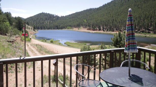 A deck with a table and chairs overlooking a lake surrounded by forested hills. - Fawn Haven on the Lake (Bailey)