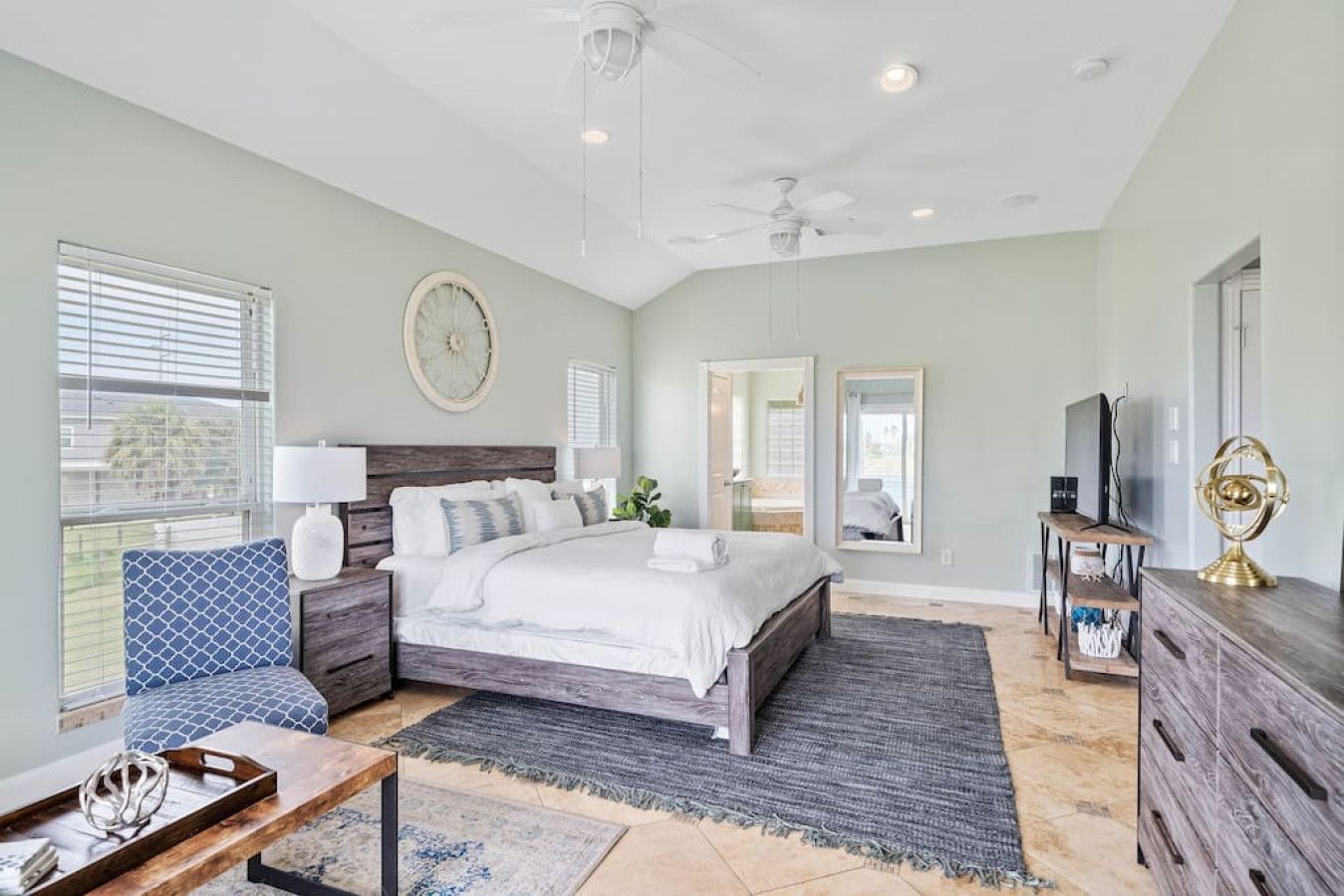 Une chambre à coucher comprenant un lit, des tables de chevet, une commode, un téléviseur et un ventilateur de plafond.