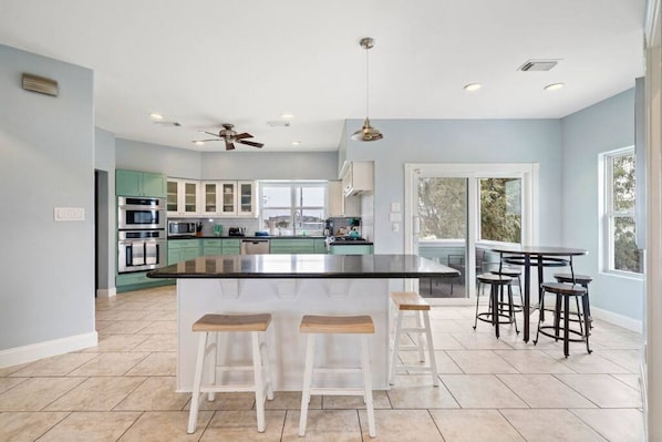 Una cocina moderna con una isla central, taburetes de bar y un comedor con mesa y sillas.