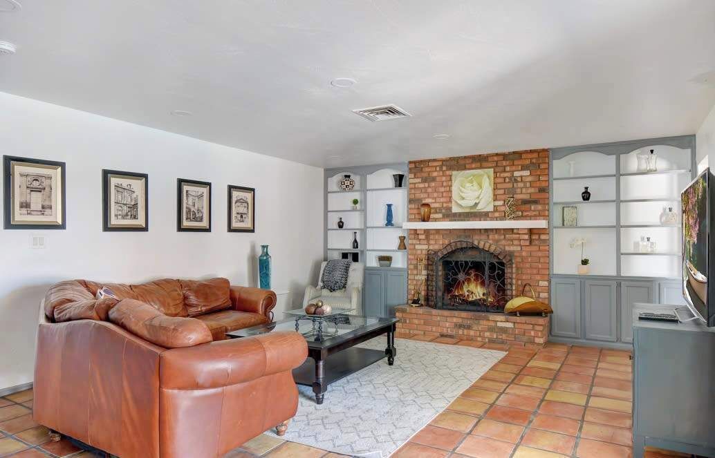 A living room with a leather sofa, a coffee table, a fireplace, and framed artwork on the wall.