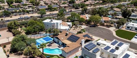 Un quartier résidentiel avec des maisons, des panneaux solaires, une piscine et une vue dégagée sur les montagnes lointaines.
