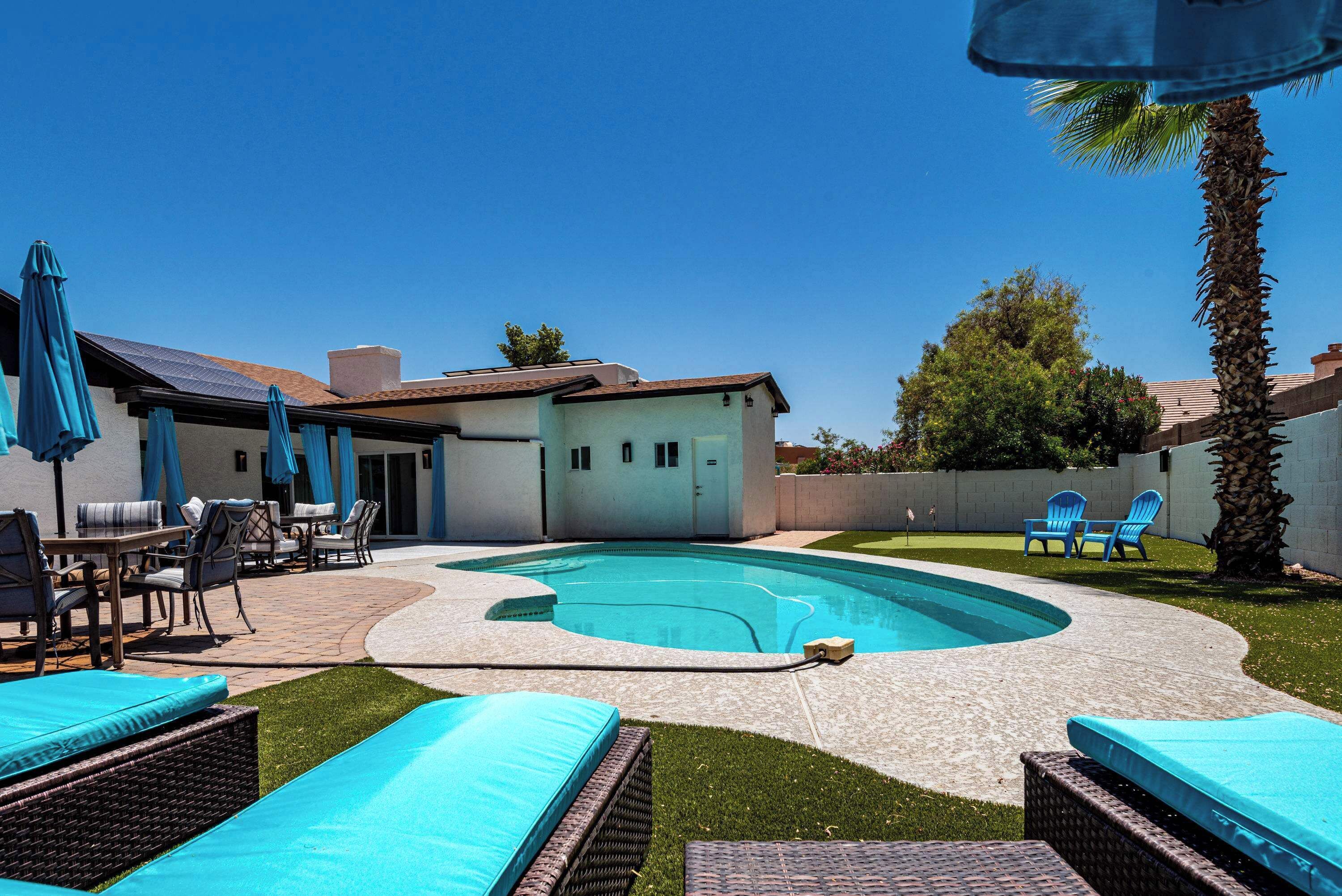 A backyard with a swimming pool, patio furniture, and a small building.