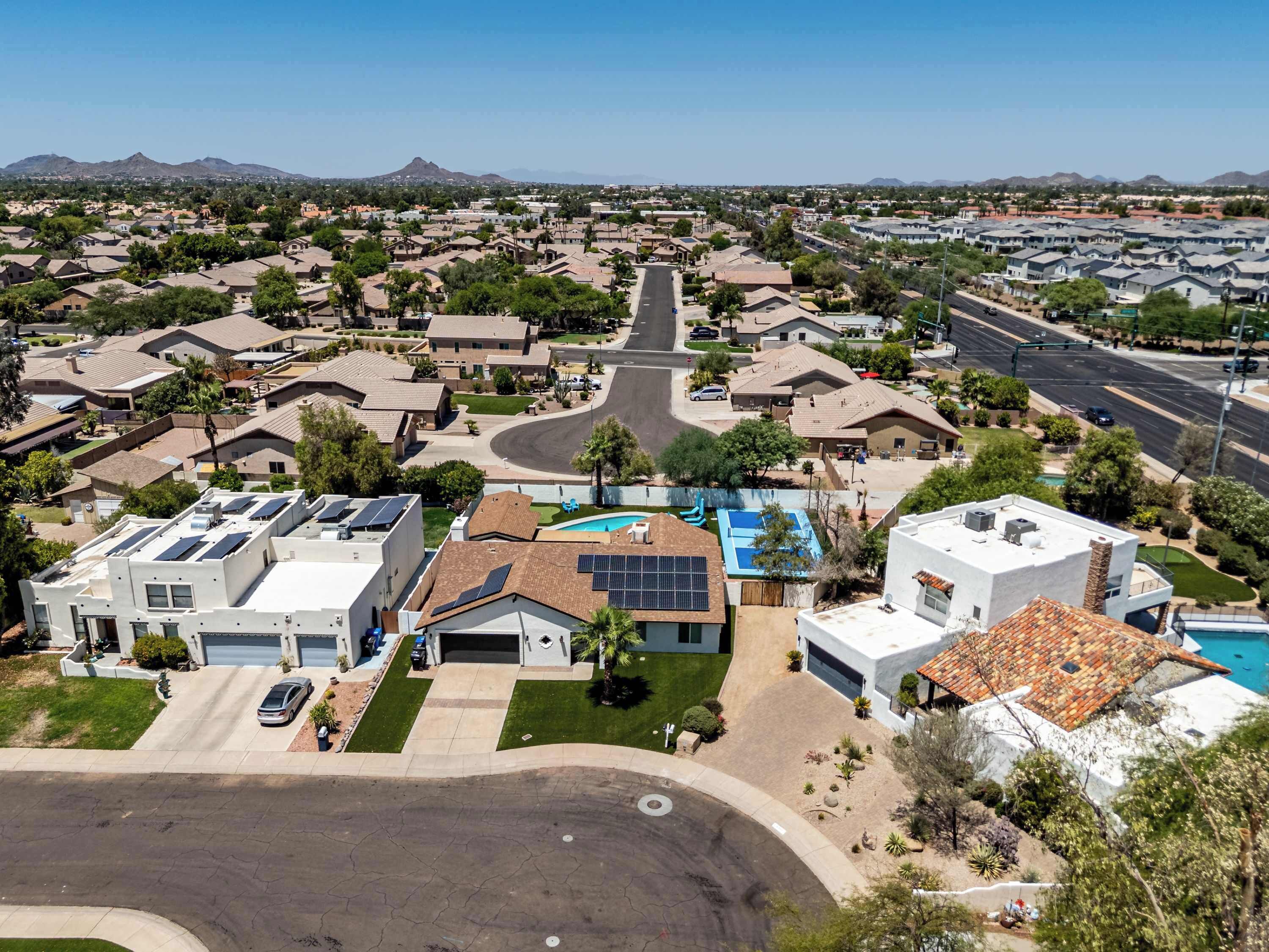 A residential area with houses, a swimming pool, and solar panels on rooftops.