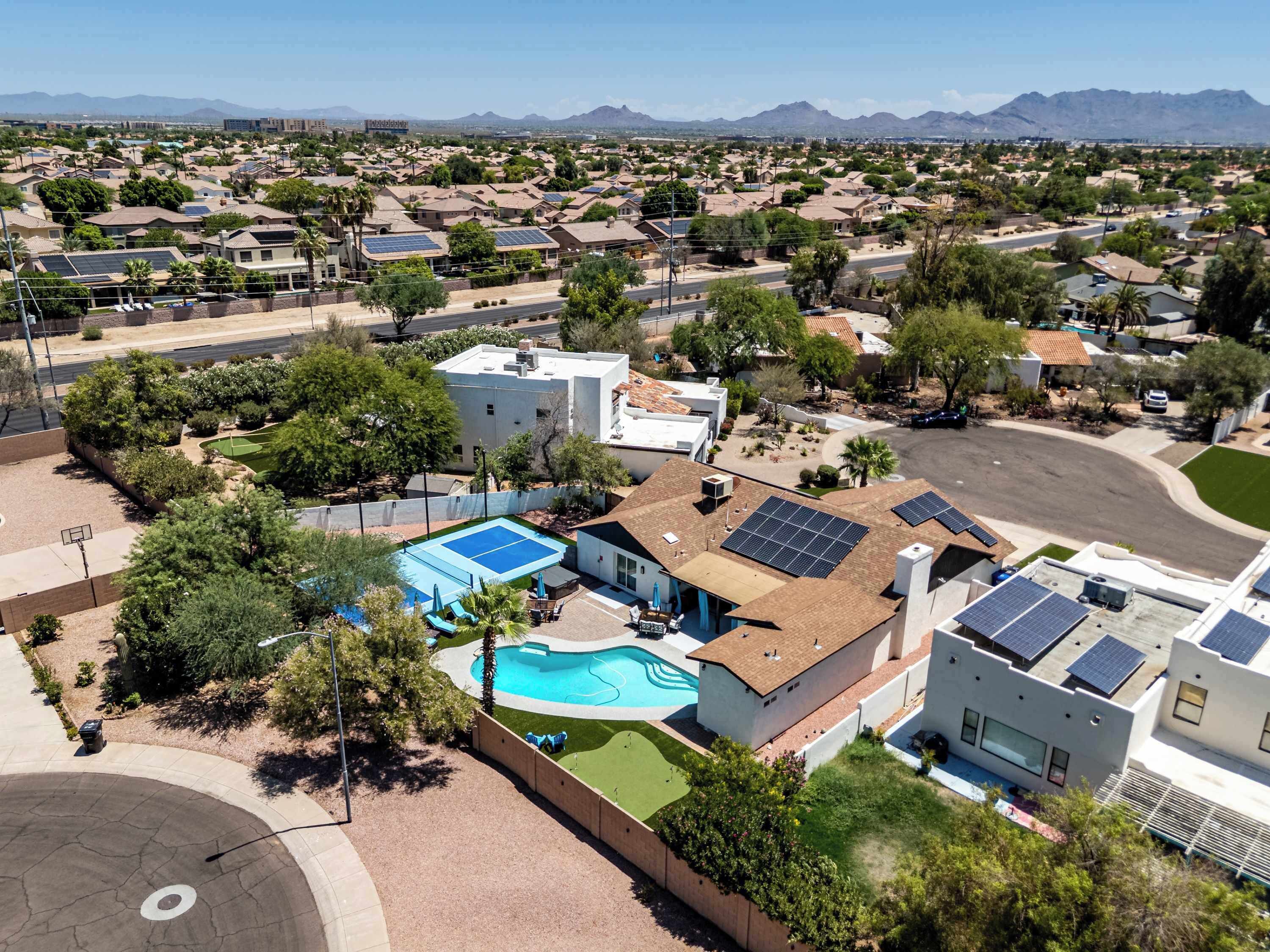 A residential area with a swimming pool, solar panels, and a basketball court.